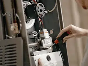 Furnace repair technician inspecting internal components and wiring in Seattle, WA