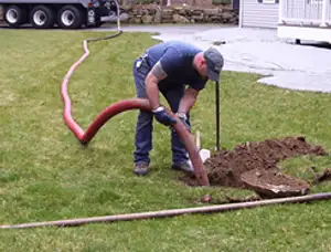 Septic pumping technician servicing a residential septic tank with a vacuum hose in Seattle, WA