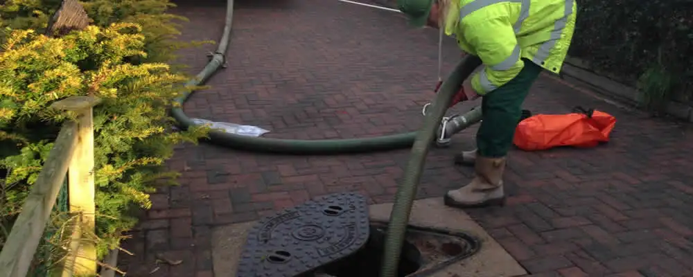 Septic tank cleaning technician servicing a septic tank with a vacuum hose in Seattle, WA