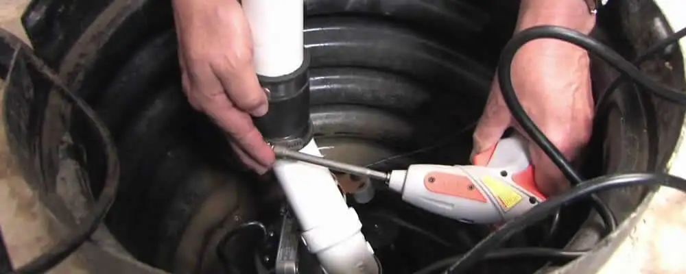 Sump pump installation technician connecting PVC discharge piping in Seattle, WA