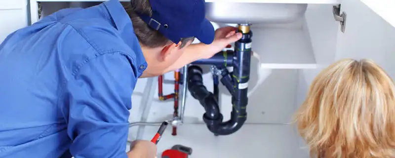 Plumber repairing under-sink drain pipes and fittings in Seattle, WA