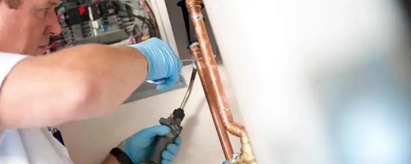 Water heater repair technician testing copper pipe connections and controls in Seattle, WA